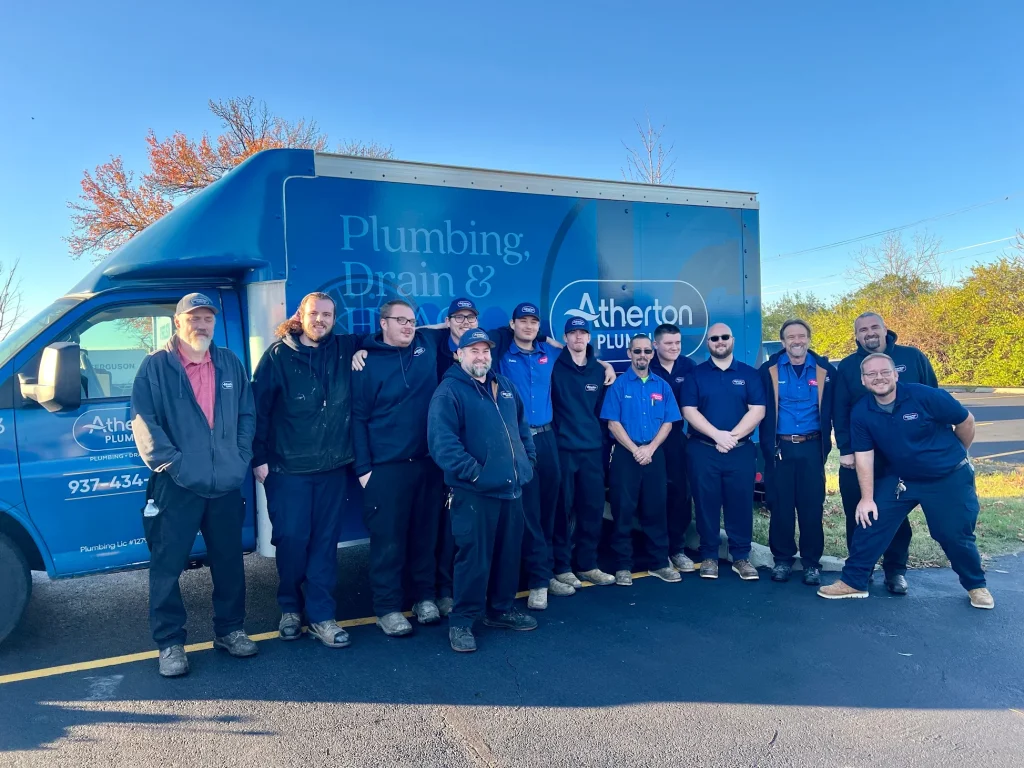 A group of people smiling and a truck in the back